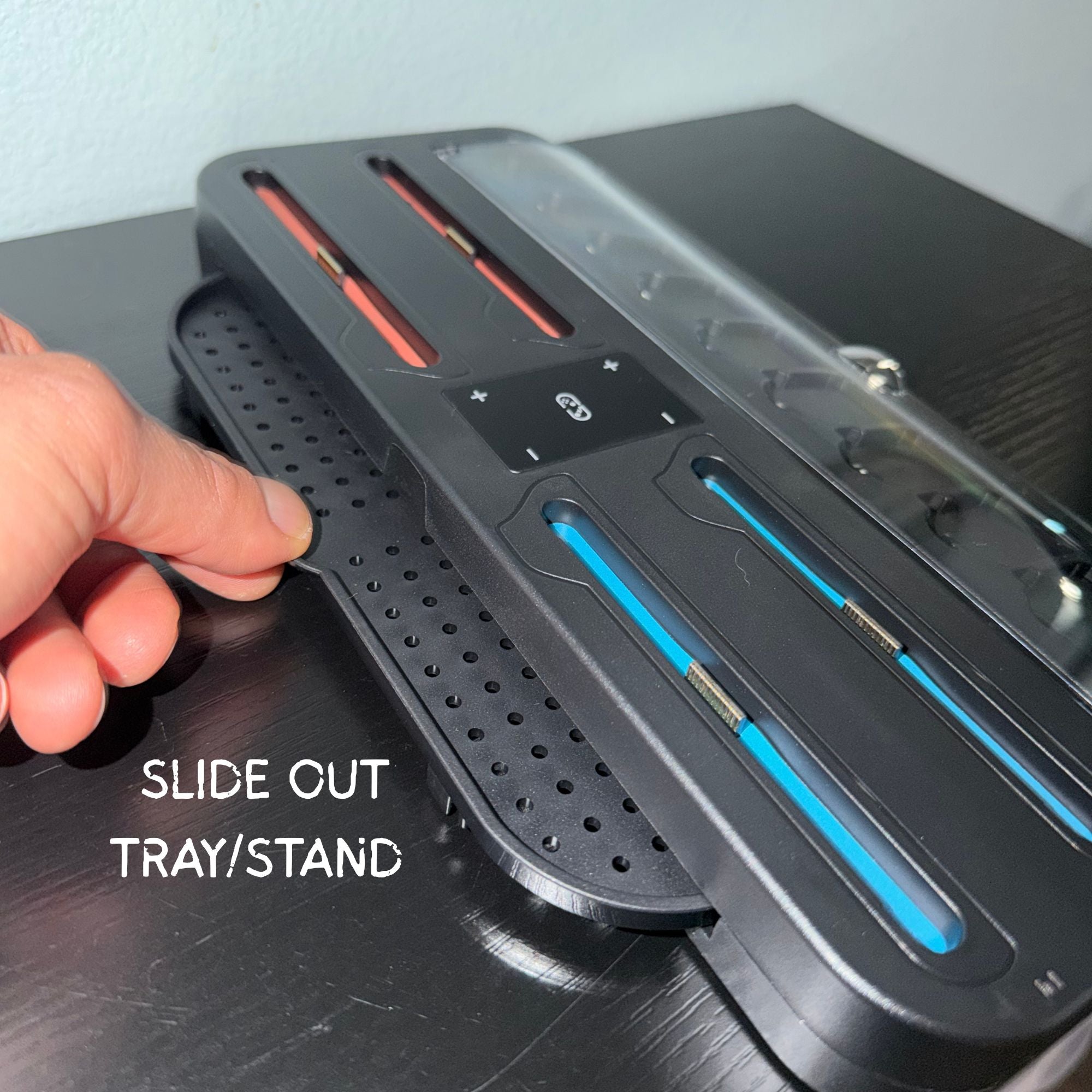 Hand holding a slide-out tray/stand with labeled text on a dark surface.
